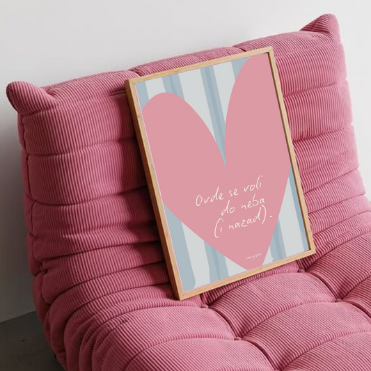 Pink cushioned chair with a framed picture of a heart on a white wall